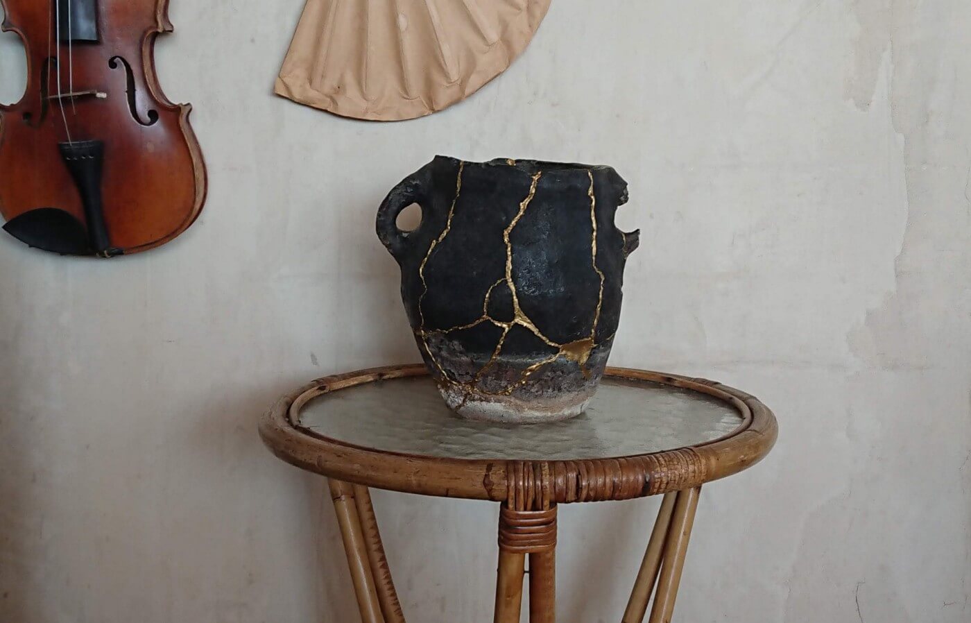 Japanese pot on a wicker repaired using Kintsugi technique with gold joining the broken black pieces together Image By Gugger— Own work, CC BY-SA 4.0, https://commons.wikimedia.org/wiki/File:Kintsugi.jpg