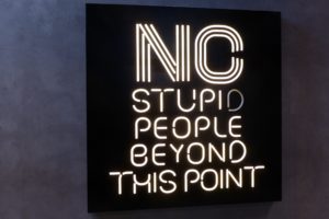 Black and white neon sign that says “No stupid people beyond this point”