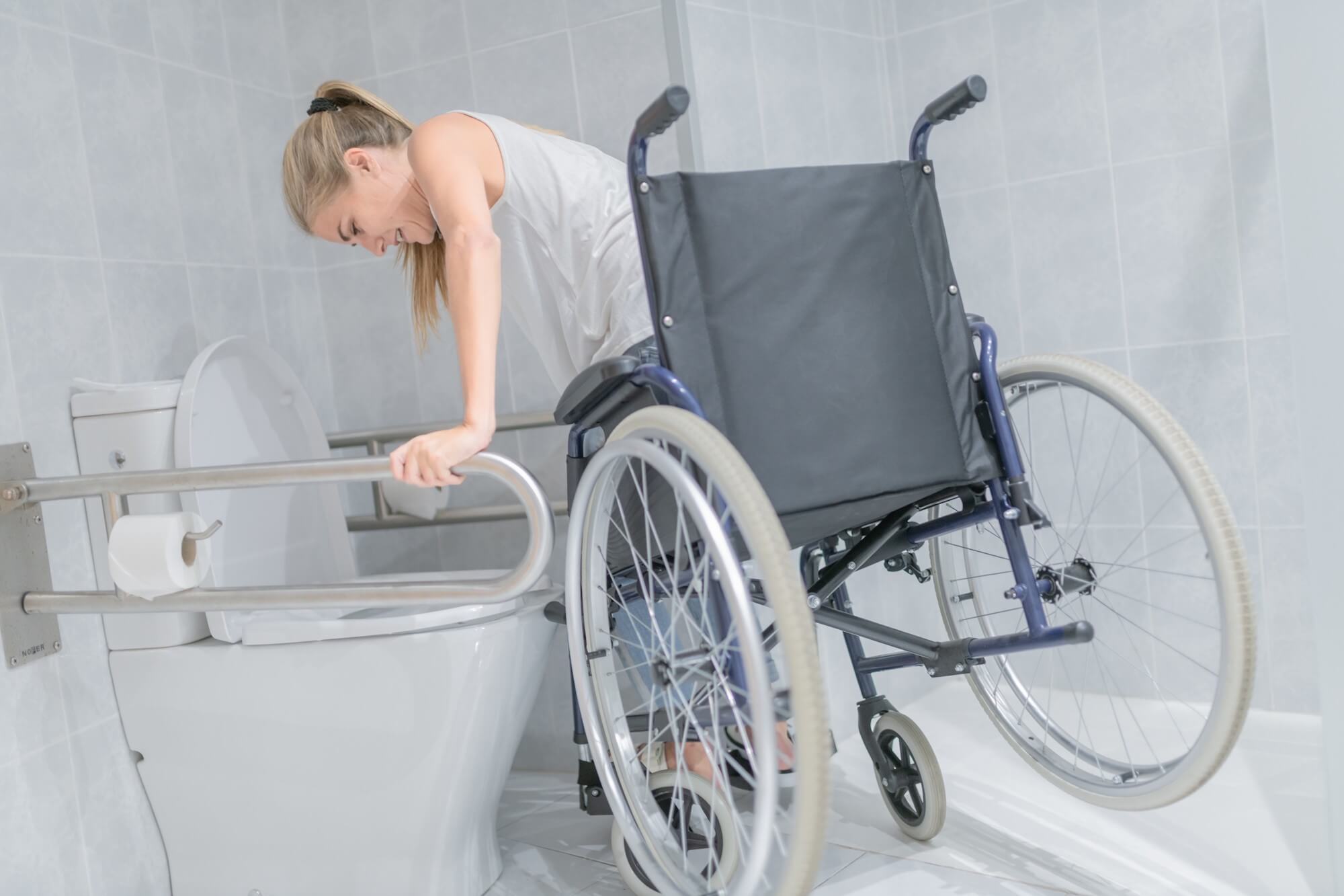 Woman wheelchair user struggling to use the restroom